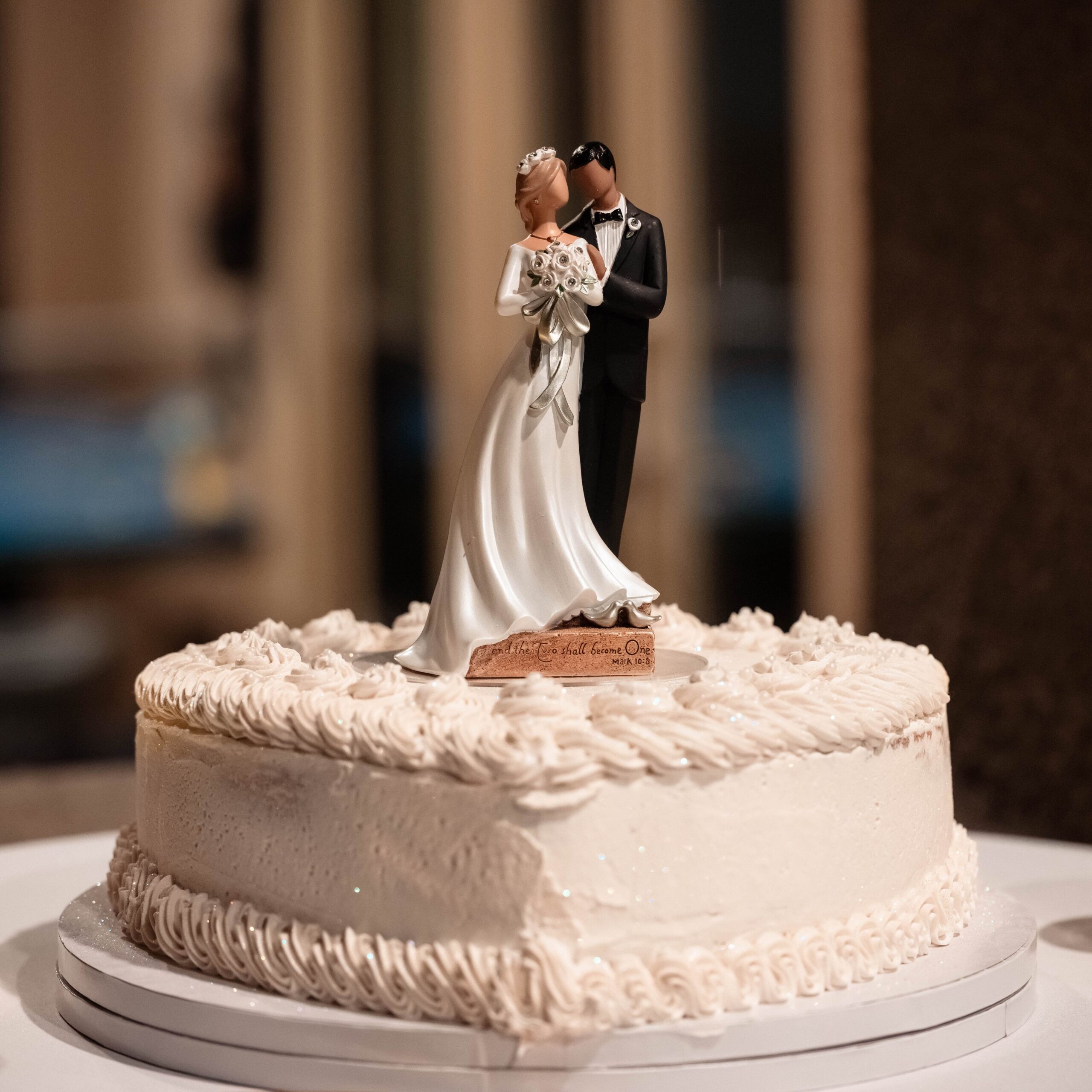 Heart shaped white cake with plastic bride and groom. 2025 wedding trends