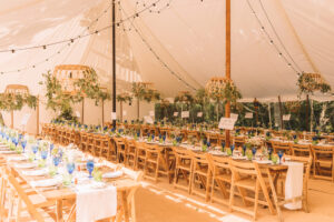 Banquet tables with greenery and festoon lights in a sailcloth marquee, planning a marquee event for a summer wedding 