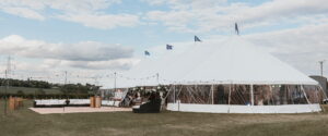 Sailcloth marquee with clear sides and festoon lighting set in the countryside - popular types of marquees for outdoor weddings.