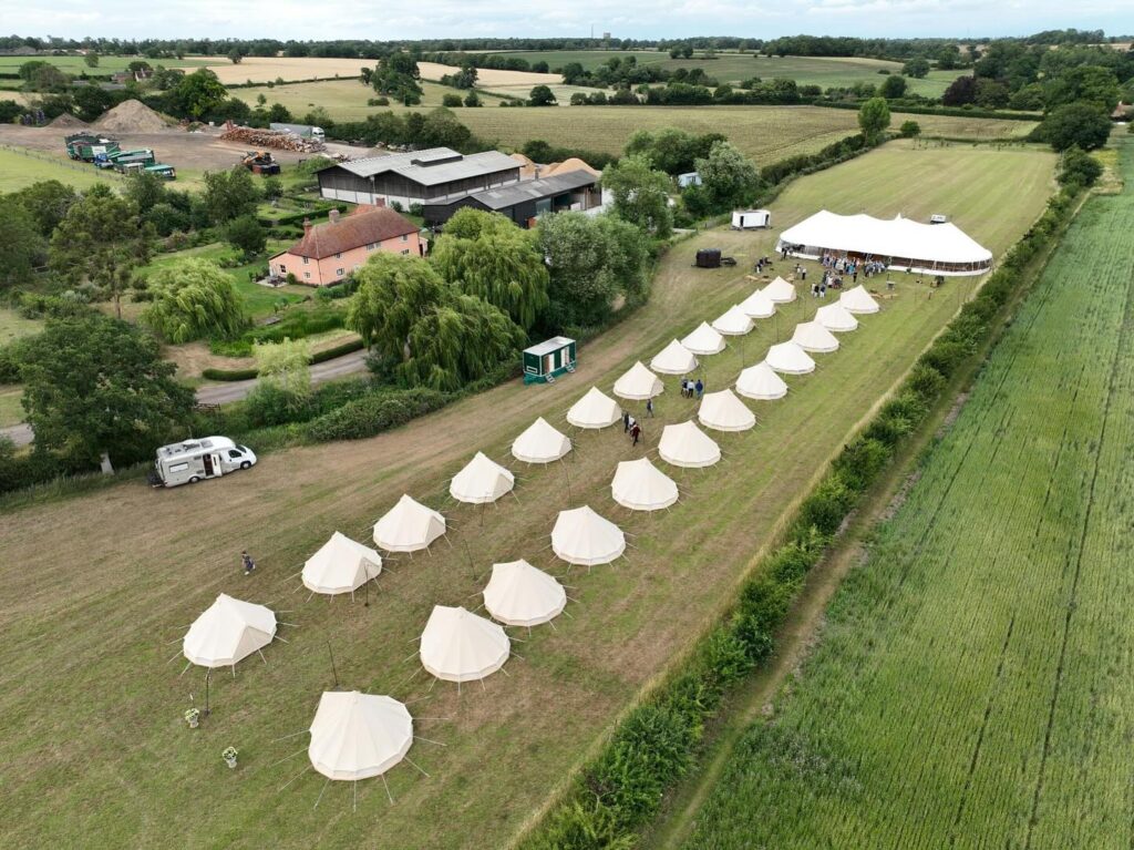 Festival marquee hire in East Anglia featuring a large event marquee and outdoor bell tent setup for a countryside festival in Essex.