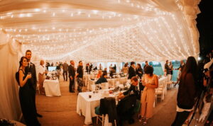 Marquee wedding party with guests under fairy lights.