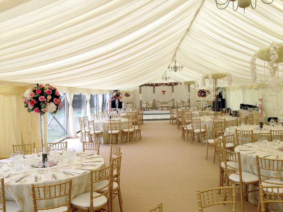 Marquee flooring options showing interior of marquee finished in white with round tables and chairs with places set for wedding.